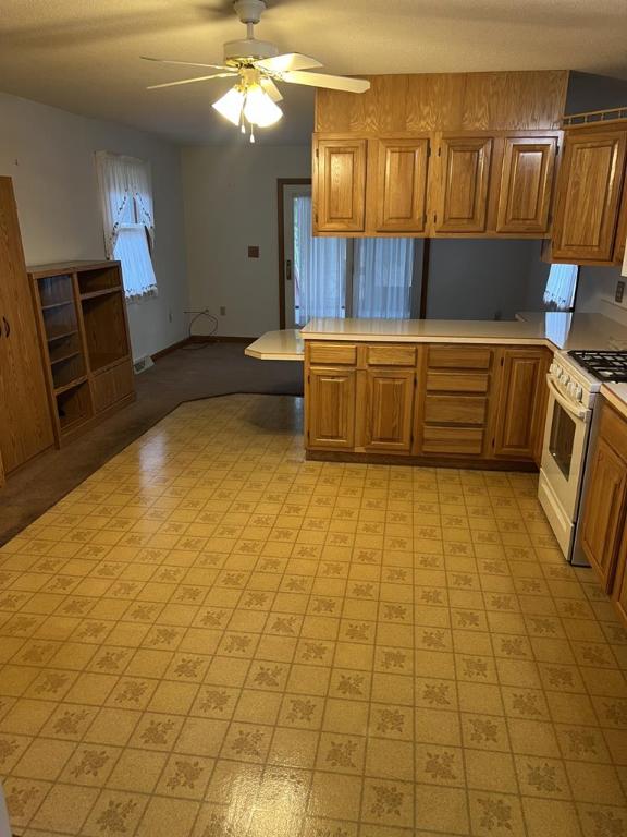 kitchen featuring kitchen peninsula, ceiling fan, and gas range gas stove