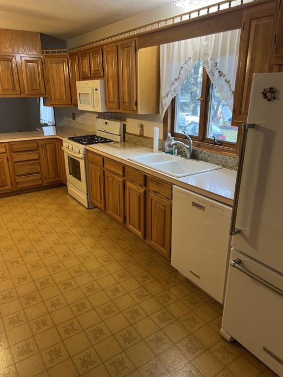 kitchen with white appliances, sink, and a textured ceiling