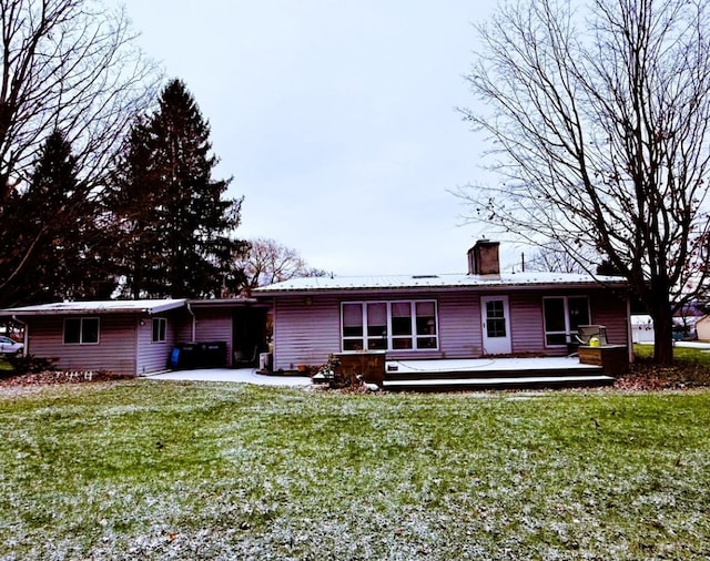 back of property with a deck and a lawn