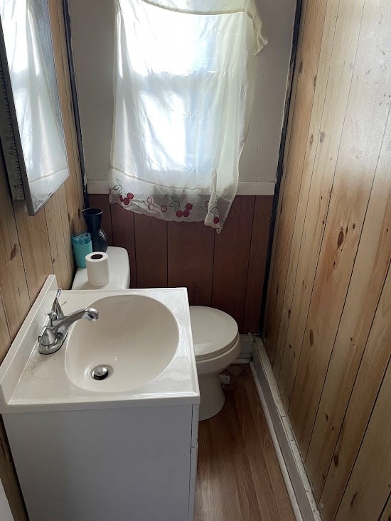 bathroom featuring vanity, hardwood / wood-style floors, toilet, and wood walls