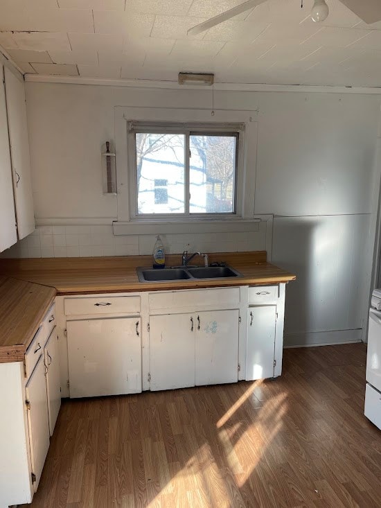 kitchen with dark hardwood / wood-style flooring, sink, white cabinets, and butcher block countertops