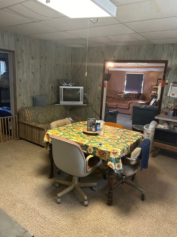 dining space with carpet flooring and wood walls