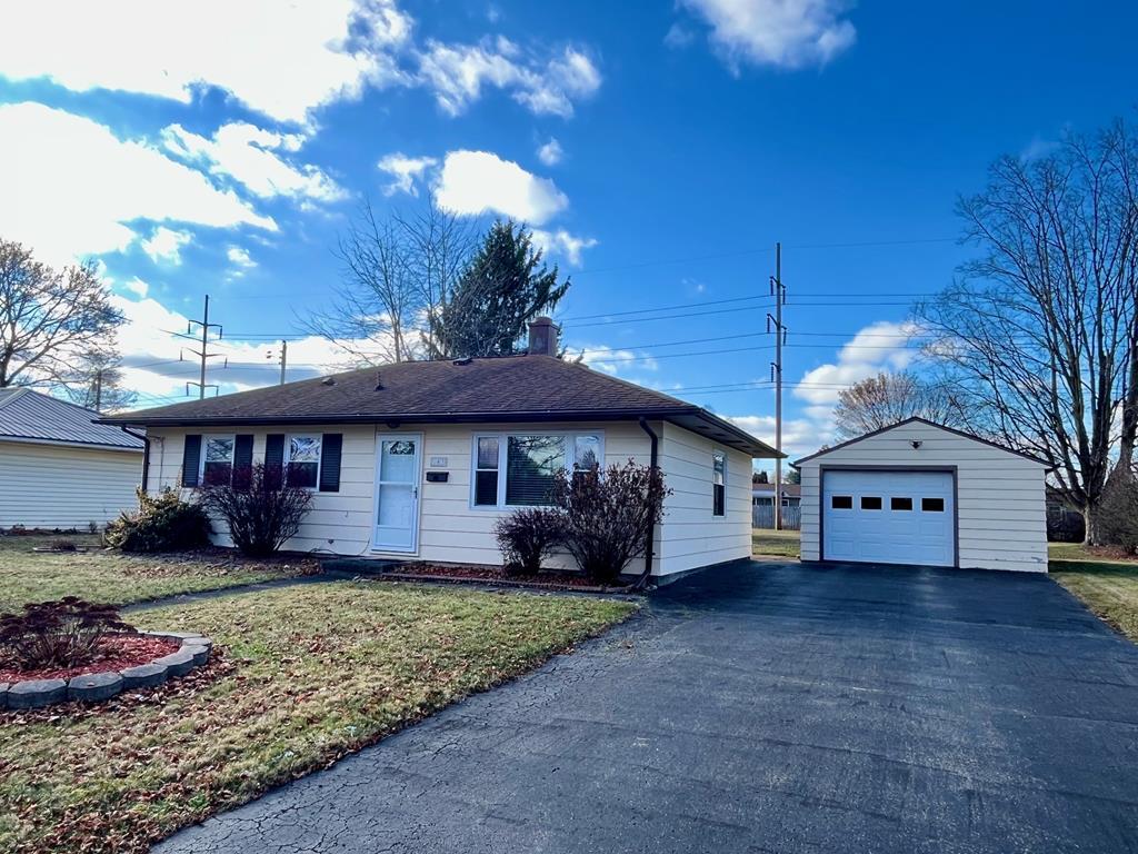 single story home featuring a garage, an outdoor structure, and a front lawn