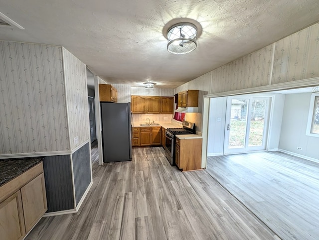 kitchen featuring appliances with stainless steel finishes, sink, light hardwood / wood-style flooring, and a textured ceiling