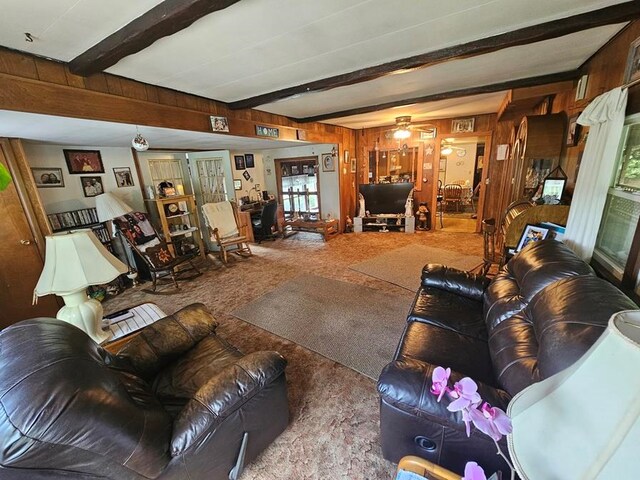 living room with ceiling fan, beam ceiling, and wood walls