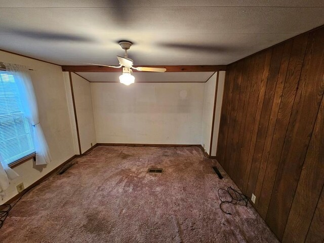 carpeted empty room featuring ceiling fan and wood walls