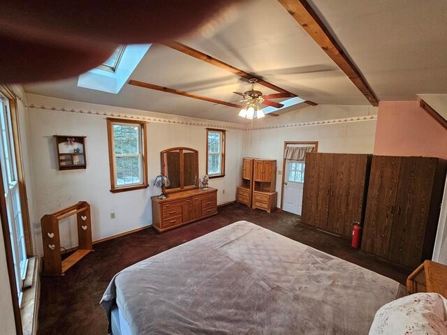 bedroom featuring ceiling fan, lofted ceiling with skylight, and dark colored carpet