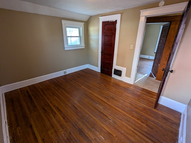 unfurnished bedroom featuring vaulted ceiling and dark hardwood / wood-style floors