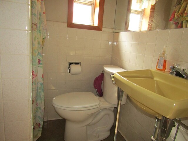 bathroom featuring a shower with curtain, toilet, tile walls, and backsplash