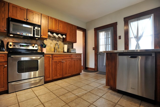 kitchen with light tile patterned flooring, stainless steel appliances, and decorative backsplash