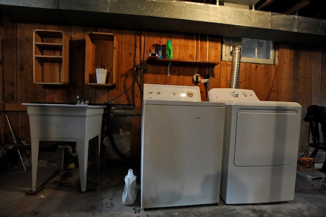 clothes washing area with washing machine and clothes dryer and wood walls