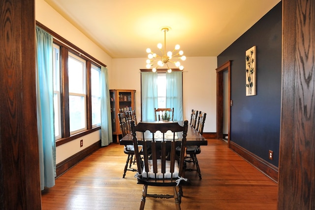 dining space with light hardwood / wood-style floors and a notable chandelier