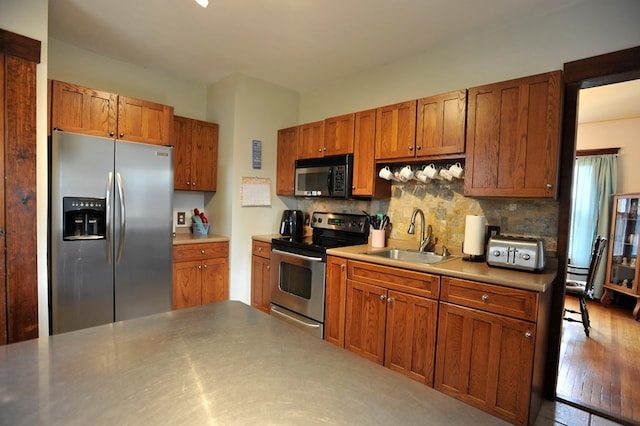 kitchen featuring stainless steel appliances, sink, decorative backsplash, and light hardwood / wood-style flooring