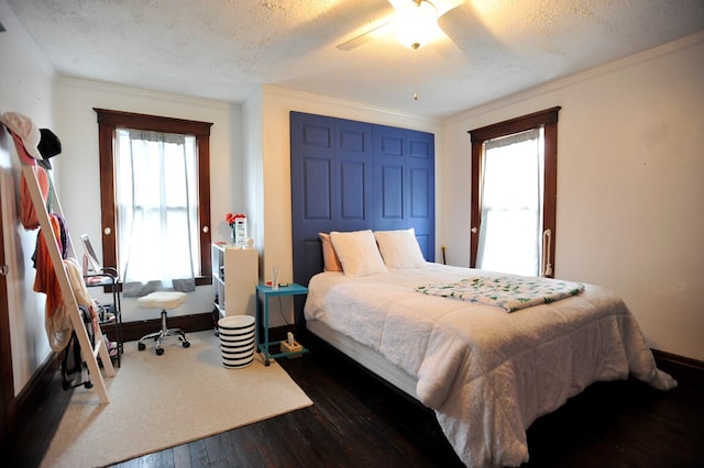 bedroom featuring ornamental molding, dark wood-type flooring, ceiling fan, and a textured ceiling