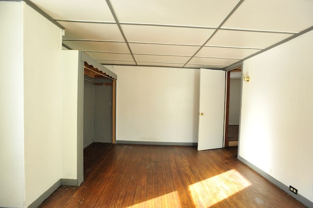 basement featuring a paneled ceiling and dark hardwood / wood-style floors