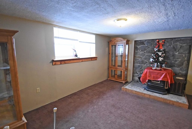 unfurnished room featuring dark carpet, a textured ceiling, and a wood stove