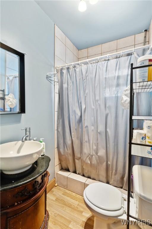 bathroom with vanity, wood-type flooring, toilet, and walk in shower