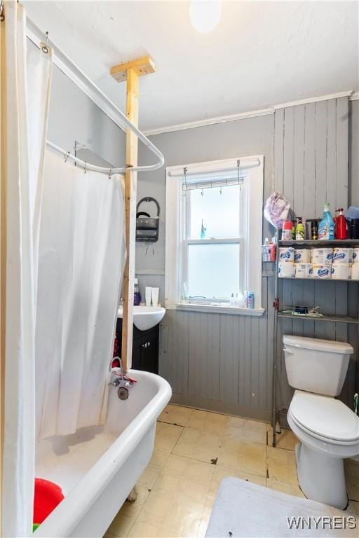 bathroom with ornamental molding, toilet, shower with separate bathtub, and wood walls