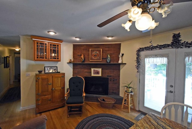 living room featuring crown molding, french doors, a brick fireplace, and light wood-type flooring