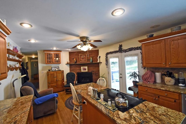 kitchen featuring french doors, a kitchen bar, hardwood / wood-style flooring, ceiling fan, and a fireplace