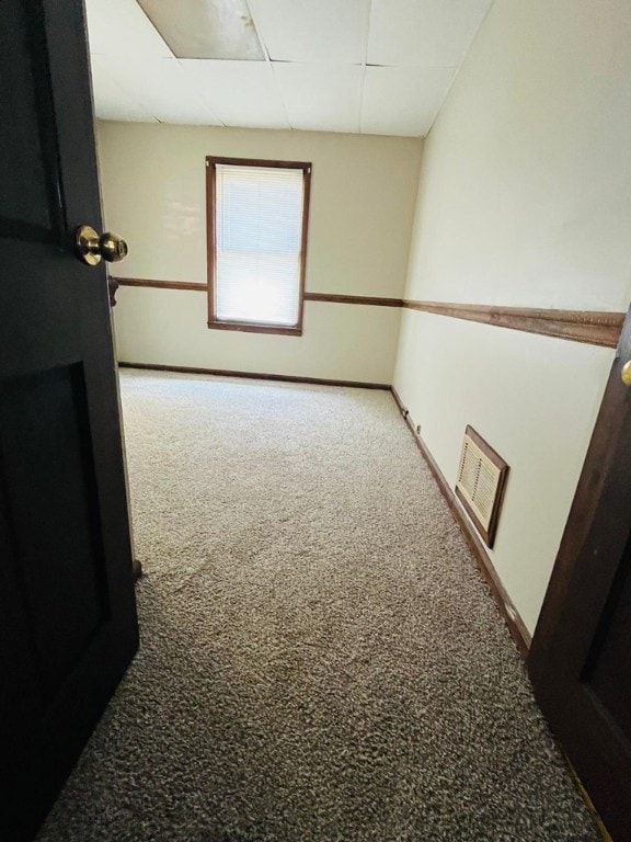 empty room with a paneled ceiling and carpet floors