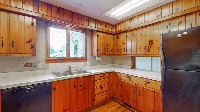 kitchen featuring wooden walls, sink, light hardwood / wood-style flooring, and black appliances