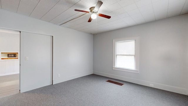 unfurnished bedroom featuring ceiling fan, carpet flooring, and a closet