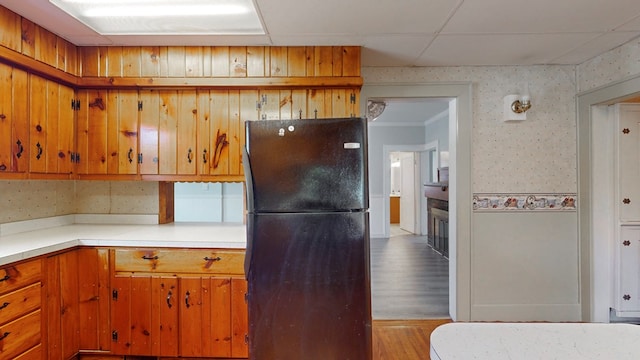 kitchen featuring black refrigerator, a paneled ceiling, and light hardwood / wood-style floors