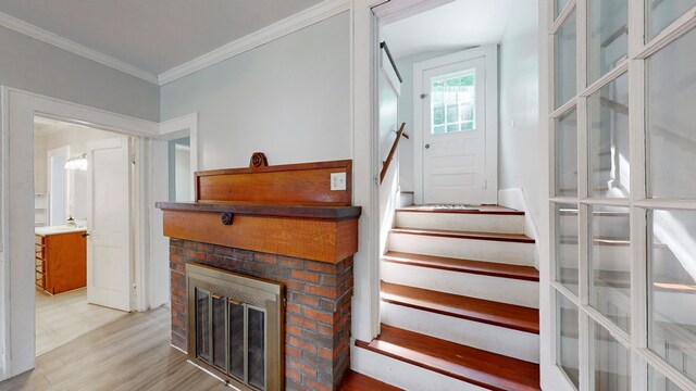 stairs featuring hardwood / wood-style flooring, a fireplace, and ornamental molding