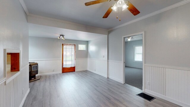 spare room with light hardwood / wood-style flooring, a healthy amount of sunlight, and a wood stove