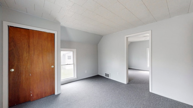 carpeted empty room with vaulted ceiling