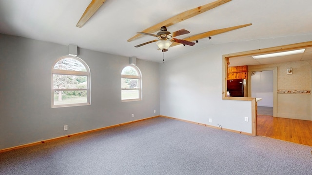 carpeted empty room with vaulted ceiling with beams and ceiling fan