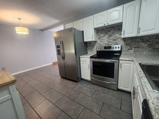 kitchen featuring dark tile patterned floors, appliances with stainless steel finishes, white cabinetry, hanging light fixtures, and backsplash