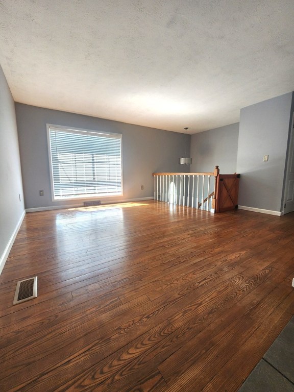 spare room with dark wood-type flooring and a textured ceiling