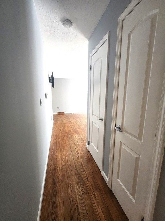 hall with dark hardwood / wood-style floors and a textured ceiling