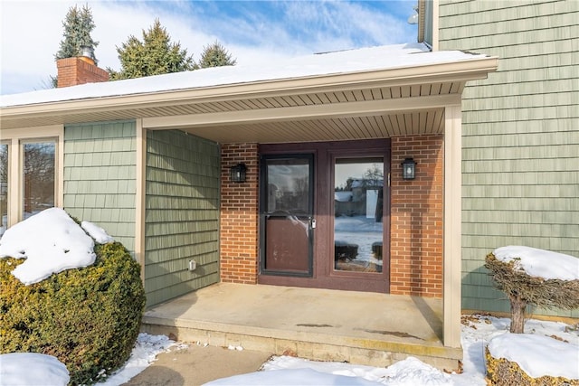 snow covered property entrance featuring covered porch