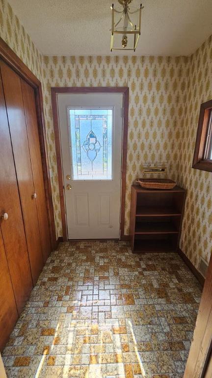 doorway to outside with a textured ceiling