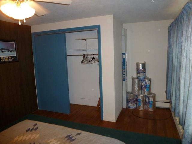 bedroom featuring ceiling fan, a baseboard heating unit, dark hardwood / wood-style flooring, and a closet