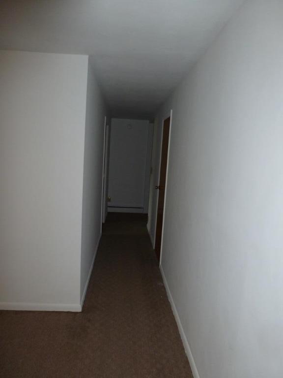 corridor featuring dark colored carpet