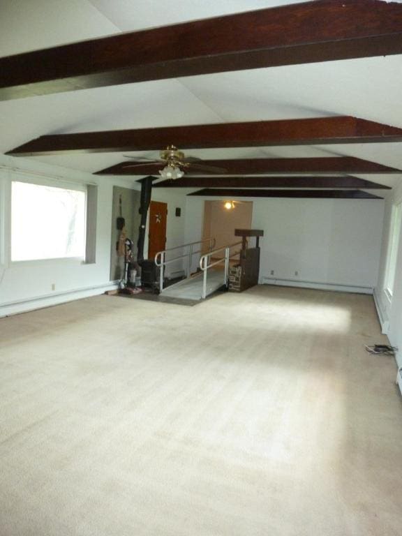 unfurnished living room featuring vaulted ceiling with beams, a baseboard radiator, and carpet