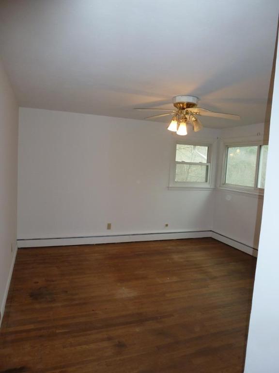 empty room with dark wood-type flooring and ceiling fan