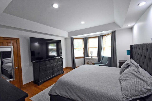 bedroom with hardwood / wood-style flooring and a raised ceiling