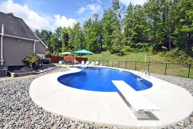 view of pool with a diving board and a patio