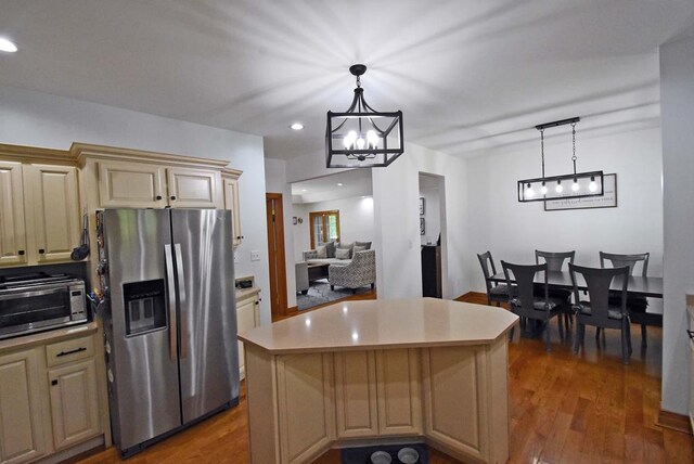 kitchen featuring dark hardwood / wood-style floors, stainless steel fridge, a center island, and decorative light fixtures