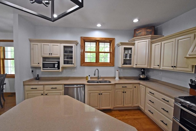 kitchen with appliances with stainless steel finishes, sink, light wood-type flooring, and cream cabinetry