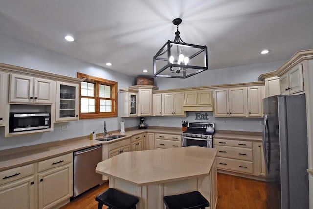 kitchen with appliances with stainless steel finishes, sink, hanging light fixtures, a center island, and cream cabinets