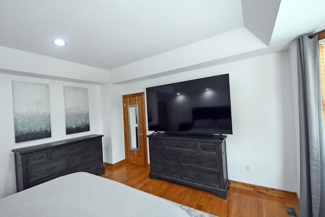 bedroom with hardwood / wood-style flooring and a tray ceiling