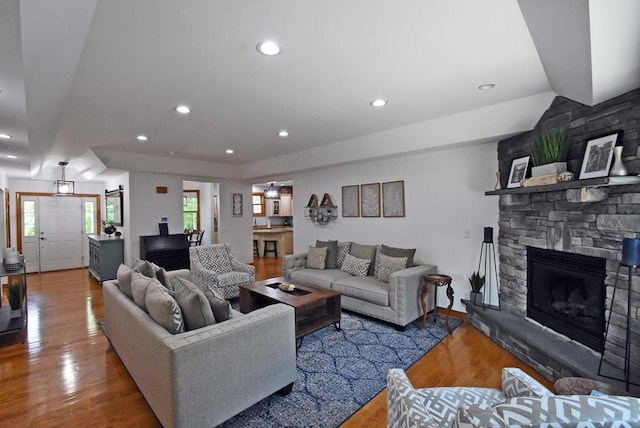 living room with wood-type flooring and a stone fireplace