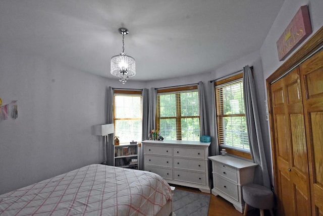 bedroom with multiple windows, wood-type flooring, and a notable chandelier