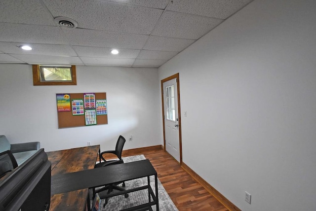 home office featuring dark wood-type flooring and a paneled ceiling